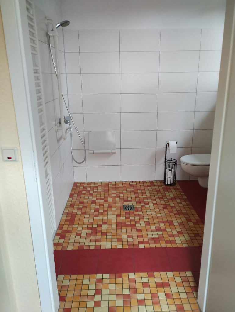 Modernes, barrierefreies Bad mit Dusche, WC und Waschbecken, vollständig gefliest