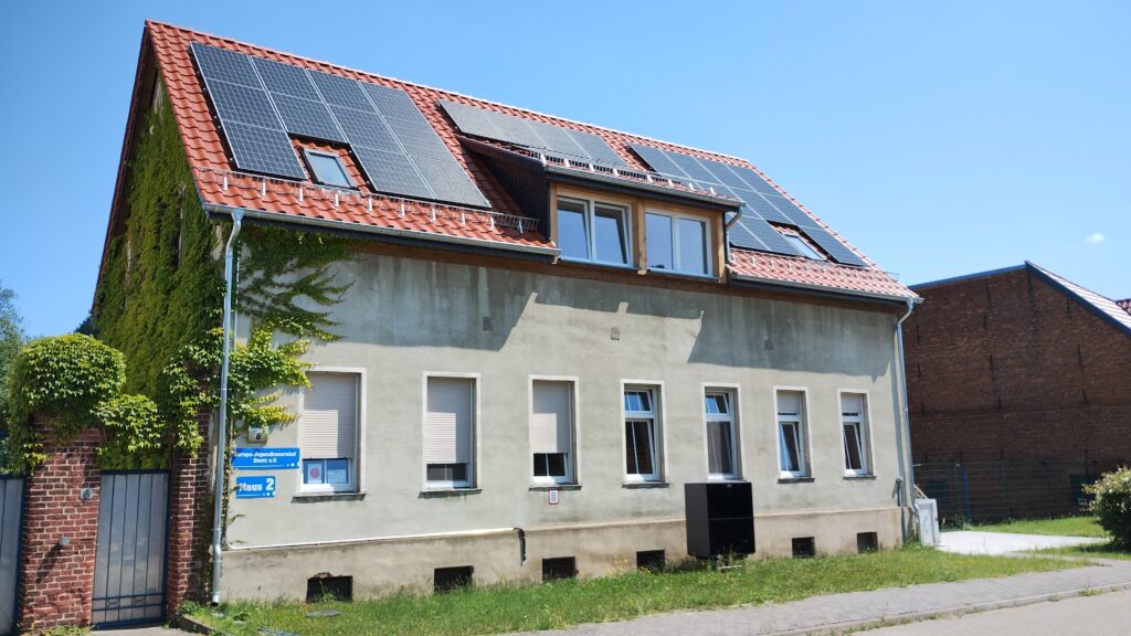 Haus eines Schullandheims, überwachsen mit grünem Efeu und Solarzellen auf rotem Ziegeldach